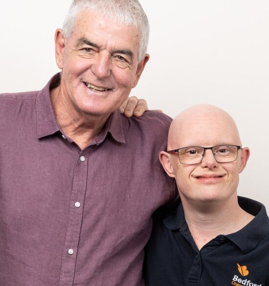 Ryan stands beside his dad, Doug, in a studio portrait against a light grey background.